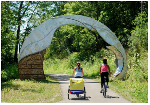 A cyclist on a trail with a sculpture nearby